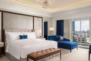 1 dormitorio con 1 cama grande y 1 silla azul en The St. Regis Jakarta en Yakarta