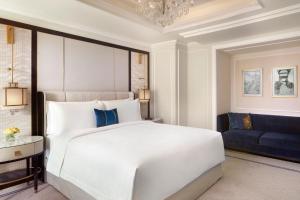 1 dormitorio con 1 cama blanca y 1 sofá azul en The St. Regis Jakarta en Yakarta