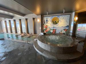 a pool with a hot tub with two people in it at Dogo Prince Hotel in Matsuyama