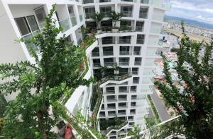 un grand bâtiment blanc avec des arbres devant lui dans l'établissement Căn hộ Condotel 5 sao Apec Tuy Hòa Phú Yên, à Tuy Hoa