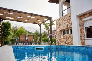 einen Pool mit einer Pergola neben einem Haus in der Unterkunft Petritis Villas in Nea Iraklitsa