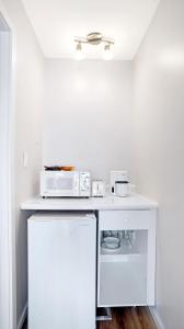 a white kitchen with a microwave and a refrigerator at Homeport Motel in Lunenburg