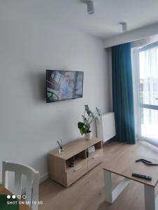 a living room with a table and a tv on the wall at Nowy w centrum in Giżycko