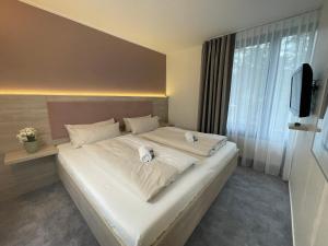 - une chambre avec un grand lit blanc et une télévision dans l'établissement Hotel Park Soltau, à Soltau