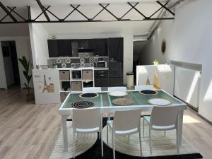 una cucina con tavolo e alcuni elettrodomestici bianchi di Loft & Spa LE FAUBOURG SAINT MARTIN a Senlis