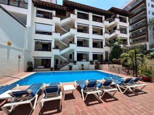 een zwembad met ligstoelen en een gebouw bij Vallarta Sun Suites in Puerto Vallarta