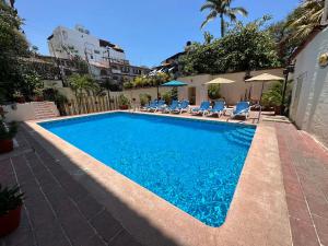 een zwembad met stoelen en parasols bij Vallarta Sun Suites in Puerto Vallarta