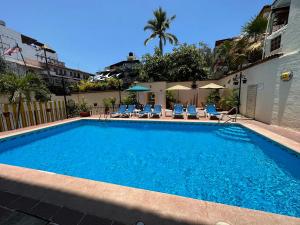 een groot blauw zwembad met stoelen en een gebouw bij Vallarta Sun Suites in Puerto Vallarta