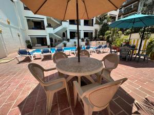 een tafel met stoelen en een parasol op een patio bij Vallarta Sun Suites in Puerto Vallarta