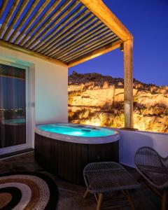 een hot tub op een patio met 2 stoelen bij Vrachos Suites Mykonos in Mykonos-stad