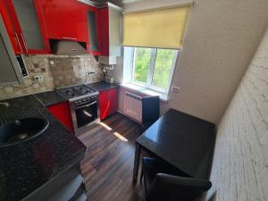 widok na kuchnię z czerwonymi szafkami w obiekcie Apartment Plaza w mieście Szymkent