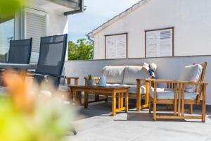 eine Terrasse mit Stühlen, einem Tisch und einem TV in der Unterkunft Apartment and Rooms Dalmatiko in Vodice