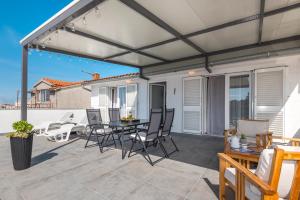 eine Terrasse mit Markise sowie einem Tisch und Stühlen in der Unterkunft Apartment and Rooms Dalmatiko in Vodice