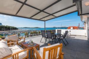 eine Terrasse mit Stühlen und Tischen und Blick auf das Wasser in der Unterkunft Apartment and Rooms Dalmatiko in Vodice