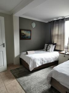 een slaapkamer met 2 bedden en een klok aan de muur bij Mulberry Gardens Self Catering in Swakopmund