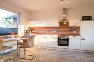 cocina con armarios blancos y pared de madera en Erholung auf der Deichschäferei mit Deichblick, en Wangerland