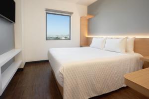 ein Hotelzimmer mit einem großen Bett und einem Fenster in der Unterkunft GAMMA Querétaro in Querétaro