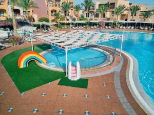 a pool at a resort with a rainbow and a slide at Jaz Makadi Saraya Resort in Hurghada