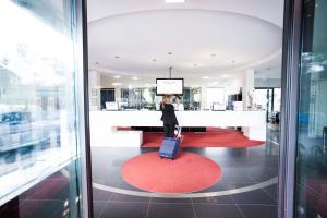 une femme debout dans un hall avec une valise dans l'établissement Hotel Schloss Montabaur, à Montabaur