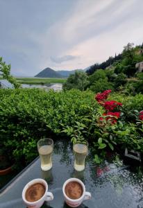 deux tasses de café sur une table à côté des fleurs dans l'établissement JOCKER, à Virpazar