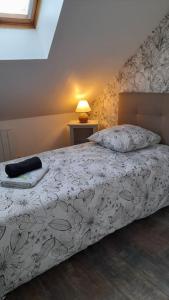 een slaapkamer met een bed met een witte deken en een lamp bij les galipes in Hautvillers