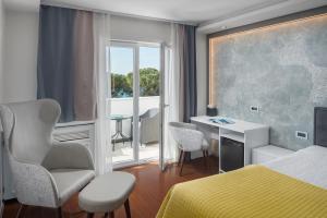 1 dormitorio con cama, escritorio y ventana en Hotel Tomi, en Portorož