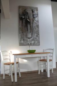 a white table with two chairs and an elephant painting on the wall at Ferienwohnung Luna in Trier