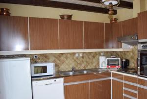 a kitchen with wooden cabinets and a sink and a microwave at Chez Vivi et Jean Pierre Maison 8 à 9 personnes au calme vue montagne WIFI in Gérardmer