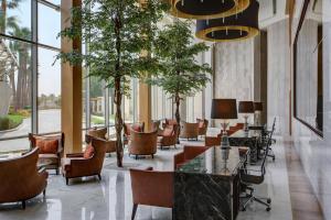 una hall con sedie, tavoli e finestre di Sheraton Jeddah Hotel a Gedda