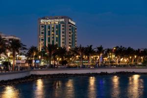 Un palazzo alto di notte con un corpo d'acqua di Sheraton Jeddah Hotel a Gedda