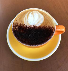 een kop koffie op een geel bord op een tafel bij Olympia by the lake in Lausanne