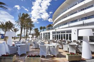 a patio with white chairs and tables in front of a building at Grupotel Acapulco Playa - Adults Only in Playa de Palma