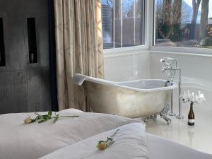 een badkamer met een bad naast een bed bij Merangardenvilla adults only in Merano