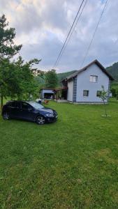 een zwarte auto geparkeerd in een tuin voor een huis bij Vila MM Boračko jezero in Konjic