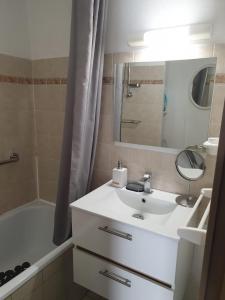 bagno con lavandino, vasca e specchio di Appartement vacances cap d’agde a Cap d'Agde