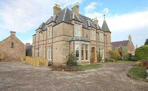 una gran casa de ladrillo con una entrada delante de ella en Duchally House, en Nairn