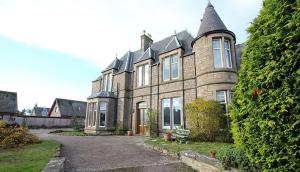 una gran casa de ladrillo con torreta en Duchally House, en Nairn