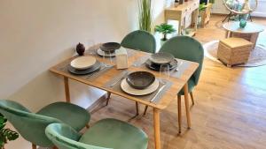 uma mesa de madeira com cadeiras verdes à volta em Appartement Design em Fréjus