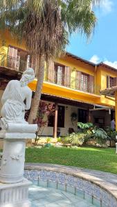 une statue en face d'un bâtiment avec un palmier dans l'établissement Hotel Vila Bavária Petrópolis, à Petrópolis