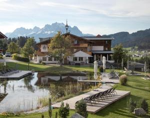 un lodge avec un étang en face d'un bâtiment dans l'établissement Hotel Chalets Grosslehen, à Fieberbrunn