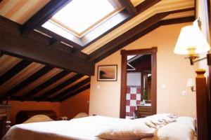 een slaapkamer met een plafond en een dakraam bij Posada Punta Ballota in Suances