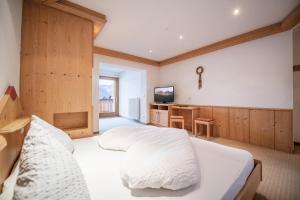 a bedroom with a large white bed and a desk at Gasthof Teiser Stern in Funes