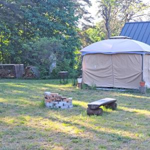 een tent in een veld met houtblokken en een bank bij Kapteni suvekodu in Laulasmaa