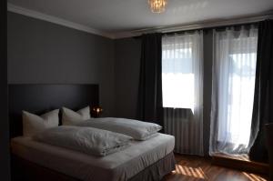 um quarto com uma cama com lençóis brancos e uma janela em Hotel Rheinstein em Rüdesheim am Rhein