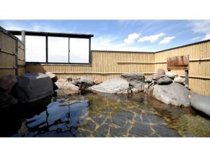 un estanque con rocas frente a un edificio en Tennen Onsen Kakenagashi no Yado Hotel Pony Onsen - Vacation STAY 50911v, en Towada