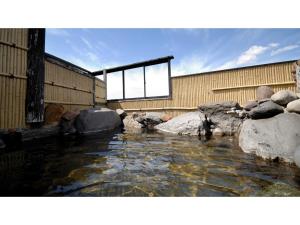 una piscina de agua con rocas frente a un edificio en Tennen Onsen Kakenagashi no Yado Hotel Pony Onsen - Vacation STAY 50911v, en Towada