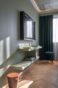 a living room with a television and a chair at Gekko House Frankfurt, a Tribute Portfolio Hotel in Frankfurt/Main