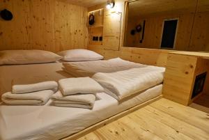 Una cama grande en una habitación de madera con toallas. en Ljubljana Capsule Hostel, en Liubliana