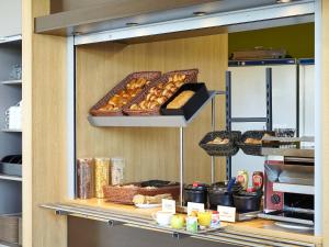 a bakery with pastries and breads on a shelf at B&B HOTEL Paris Roissy CDG Aéroport in Roissy-en-France