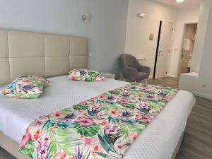 um quarto com uma cama com um cobertor florido em Hotel Ancora Mar na Nazaré